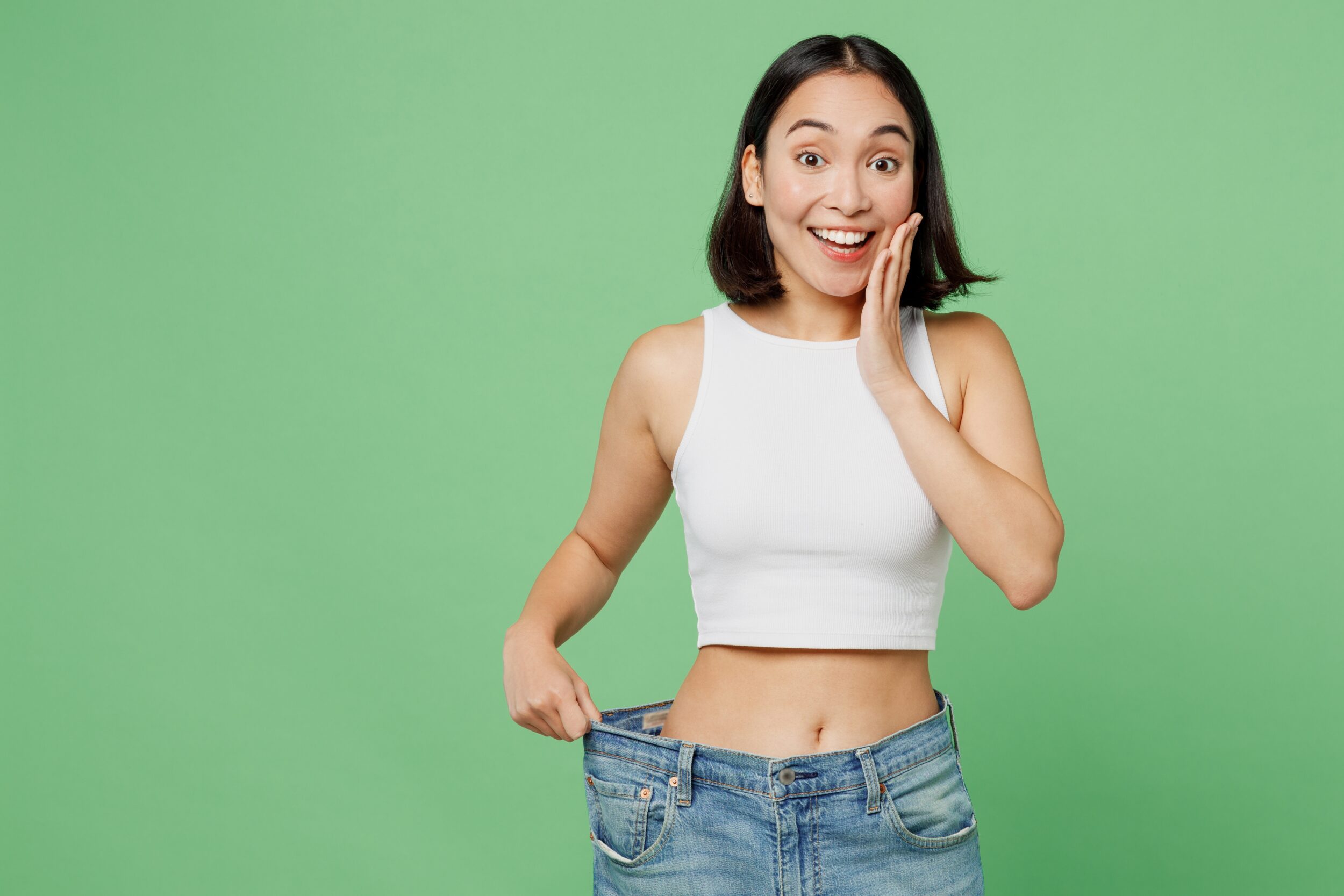 Woman smiling in baggy jeans showing weight loss and body contouring in Andover, MA