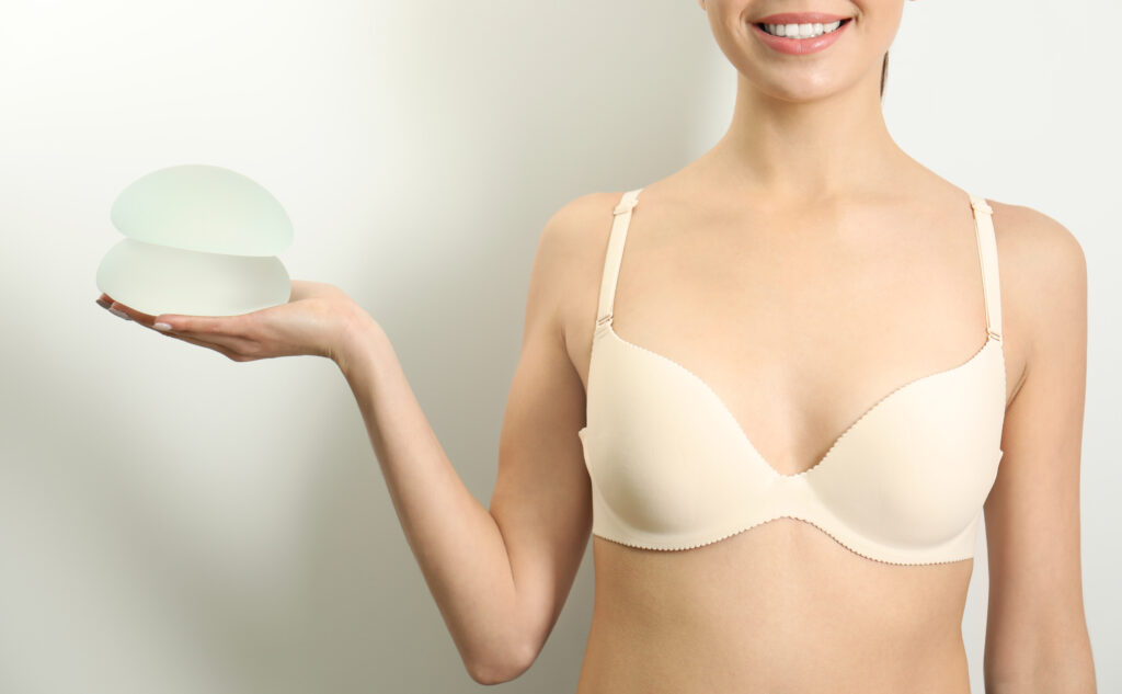 Close up of woman's chest as she holds breast implants after removal in Andover, MA