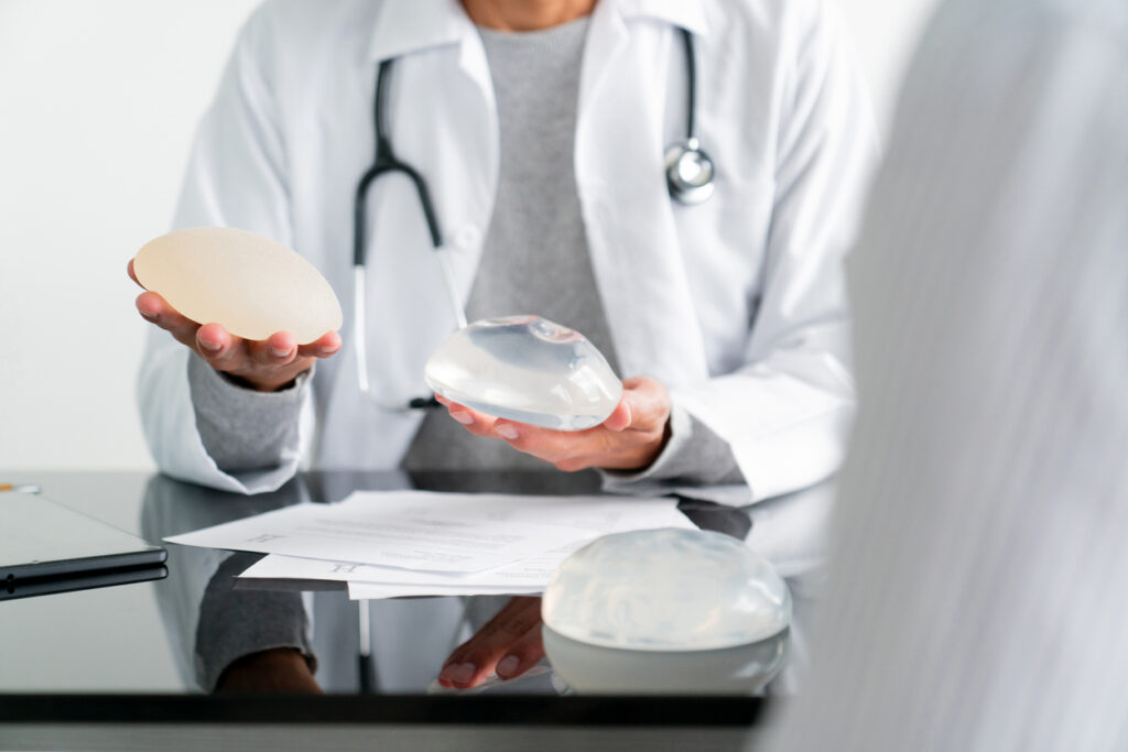 Plastic surgeon holding breast implants during a consultation.